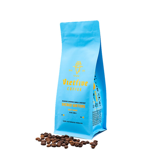 A blue bag of light roast whole bean coffee with some coffee beans displayed in front of the bag.