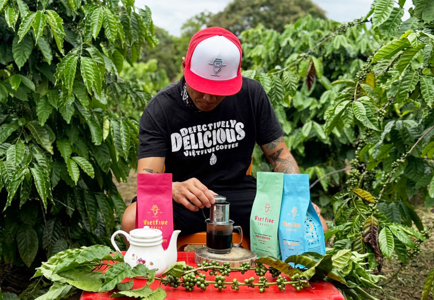 VietFive Owner  preparing coffee in a coffee plantation with coffee bags and a teapot.